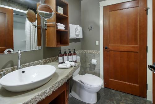 un bagno con lavandino, WC e specchio di Marvellous Mountain Condo- Pets - Pool & Hot Tub managed by Little Sister Getaways a Canmore