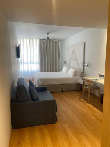 a bedroom with a bed and a couch and a table at Talayot - Adults Only in Cala Millor