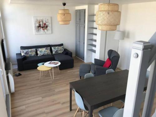 un salon avec un canapé noir et une table dans l'établissement Le duplex de Talleyrand Hyper Centre, à Reims