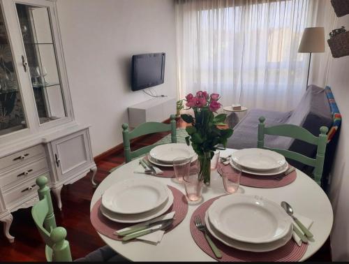 una mesa de comedor con platos y flores. en Apartamento en Milladoiro en Milladoiro