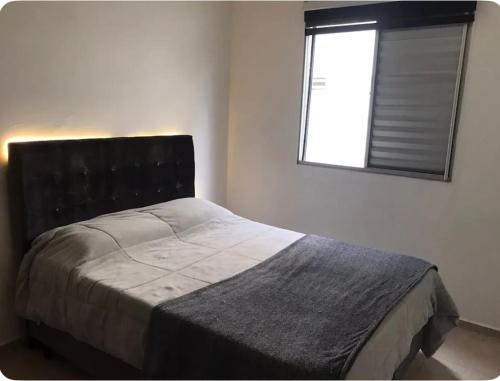 een slaapkamer met een groot bed en een raam bij Apartamento aconchegante perto do Shopping Iguatemi in Votorantim