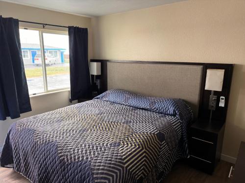 a bedroom with a bed with a striped comforter and a window at The Lodge Tulelake in Tulelake