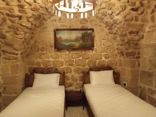 two beds in a room with stone walls at ARev BUTİK HOTEL in Mardin