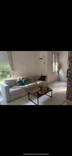 un salon avec un canapé blanc et une table basse dans l'établissement Appartement jacuzzi, à Pontault-Combault