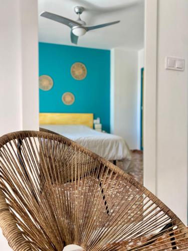 a rattan chair in a bedroom with a blue wall at Mi Oasis Azul Parking, AC, Fibra, VT-54949-V in Sueca