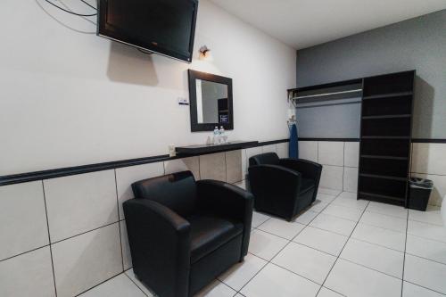a waiting room with two chairs and a flat screen tv at Hotel Maioris El Diez Culiacan in Culiacán