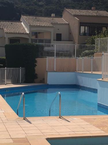 une grande piscine bleue devant une maison dans l'établissement Appartement cosy dans une résidence avec piscine, à Cavalaire-sur-Mer