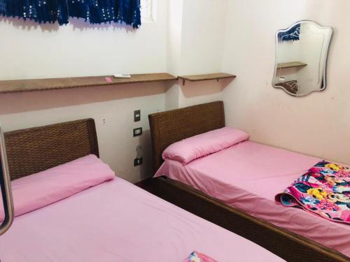 two beds in a small room with pink sheets at Porto marina in El Alamein