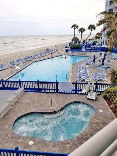 a view of two pools with chairs and a beach at Islander Beach Resort by CV in New Smyrna Beach