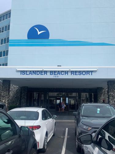 Islander Beach Resort by CV في نيو سميرنا بيتش: موقف للسيارات مع وقوف السيارات أمام منتجع على الشاطئ