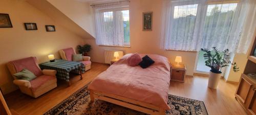 a bedroom with a bed and a chair and windows at Dom Wakacyjny U BARBASI - 7 DNI W DOBREJ CENIE ! in Chmielno