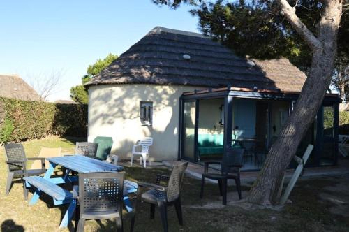 een klein huisje met een tafel en stoelen in de tuin bij Résidence ILE DES PECHEURS - Maisons & Villas pour 6 Personnes 34 in Port Leucate