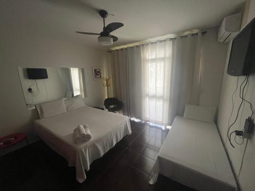 a hotel room with two beds and a television at Suíte espaçosa! Ar, Tv e banheiro privativo! in Goiânia