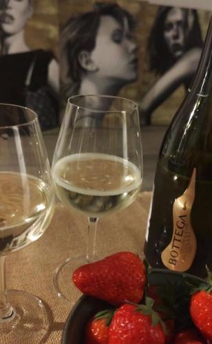 a glass of white wine next to a bottle of strawberries at LuxArt City Spa Gallery Residence Krk in Krk