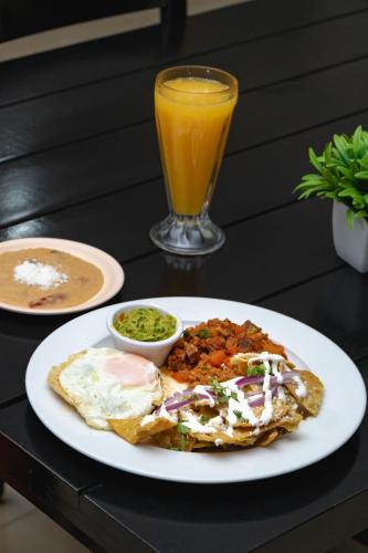 a plate of breakfast food and a glass of orange juice at Hotel Maioris El Diez Culiacan in Culiacán