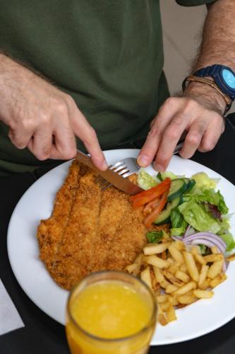 a person cutting into a plate of fish and fries at Hotel Maioris El Diez Culiacan in Culiacán