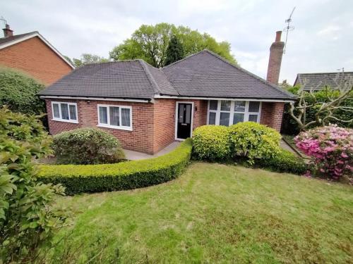 een rood bakstenen huis met een groene tuin bij Twilight House - sleeps 7, driveway, gardens in Crewe