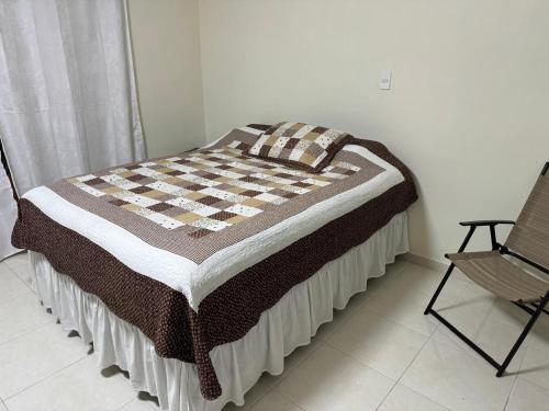 - un lit avec une couverture en damier et une chaise dans l'établissement Espectacular casa vacacional con garaje en Pereira, à Pereira