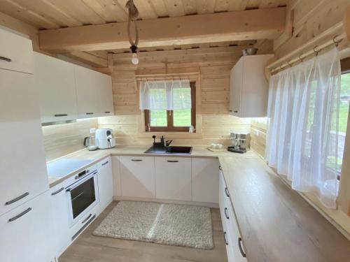 una pequeña cocina con armarios blancos y una ventana en Chata Starý Mlyn, en Habovka