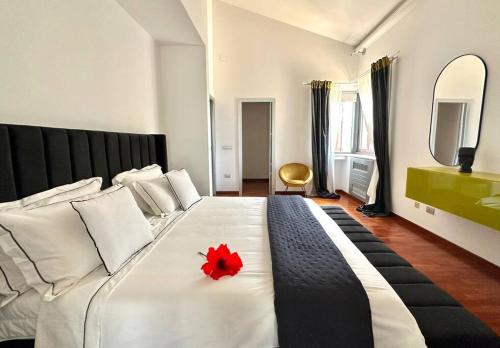 a large white bed with a red flower on it at Enchantment in the Heart of Nature in Canicattini Bagni