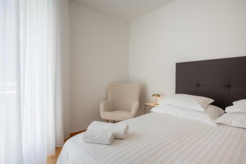 a bedroom with a white bed and a chair at Adriatic Queen Residence in Split