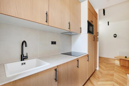 une cuisine avec un évier et des armoires en bois dans l'établissement Belleville republique, à Paris