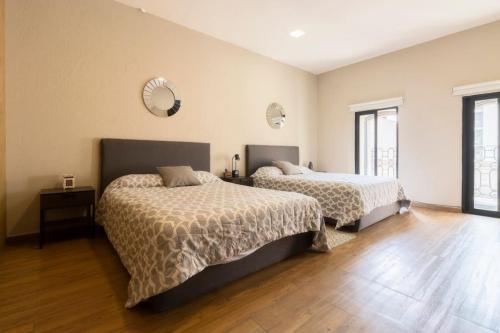 two beds in a room with wooden floors at 305 Dwntn Apt With AC and balconies fits 6 Rooftop in Mexico City