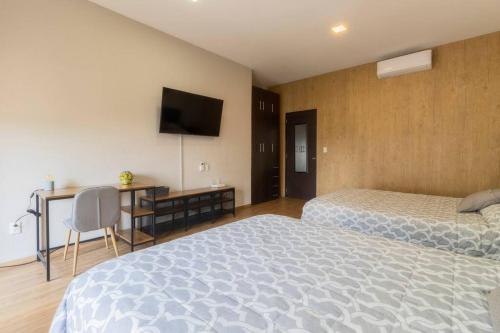 a bedroom with two beds and a desk and a television at 305 Dwntn Apt With AC and balconies fits 6 Rooftop in Mexico City