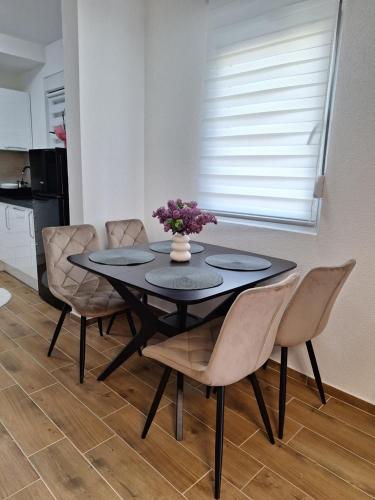 a dining room table with chairs and a vase with flowers at Apartman WIN Sokobanja in Soko Banja