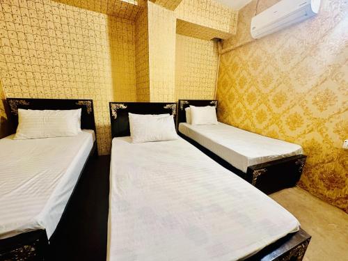 two twin beds in a room with yellow walls at Jhelum Khan Hotel in Jhelum