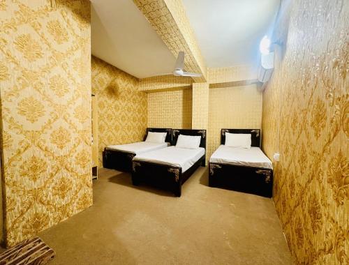 Jhelum Khan Hotel في Jhelum: يوجد سريرين في غرفة بجدران صفراء
