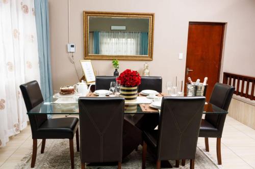 a dining room with a glass table and black chairs at Toriso Hotels Group in Nelspruit