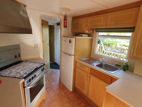 une cuisine avec un réfrigérateur blanc et un évier dans l'établissement Camping du Lac, à Égletons