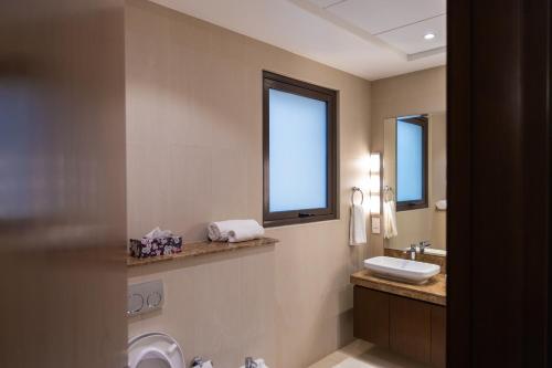 La salle de bains est pourvue d'un lavabo, de toilettes et d'une fenêtre. dans l'établissement AlZaha Villa Muscat Bay, à Mascate