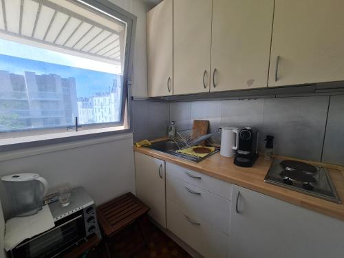 une petite cuisine avec un évier et une fenêtre dans l'établissement Luminous Studio with Air conditioning, Eiffel Tower view, à Paris