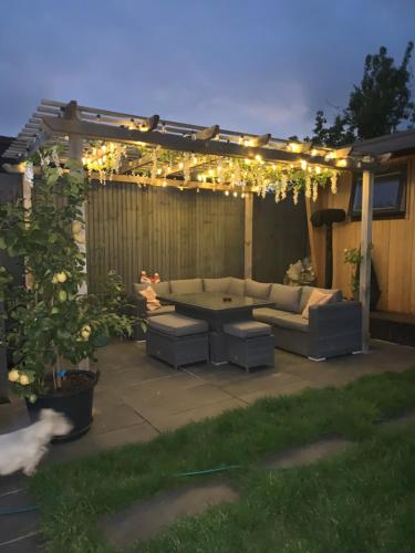 een patio met een bank en een pergola met verlichting bij Lindas LODGE Free PARKING air con plus provisions included in Hove