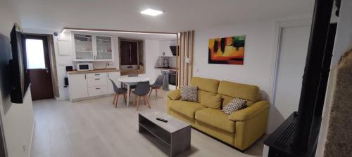 ein Wohnzimmer mit einem gelben Sofa und einem Tisch in der Unterkunft Casa bajo con jardín LaFinca Finisterre in Kap Finisterre