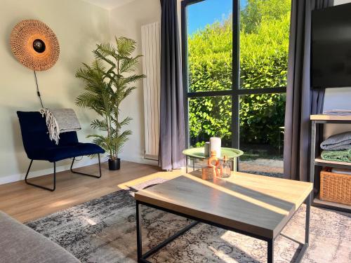 a living room with a coffee table and a large window at Vrijstaande 6 persoons Bungalow hottub en pizzaoven op vakantiepark in Ewijk