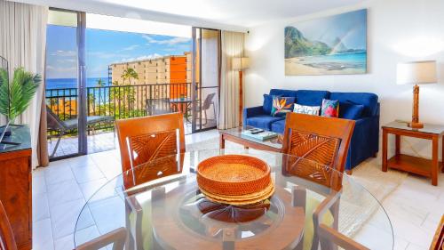 a living room with a blue couch and a glass table at Maui Westside Presents: Kaanapali Shores 733 Stunning Ocean Views NEW LISTING in Lahaina