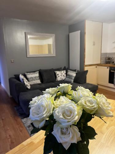 a living room with a couch and a bouquet of white roses at Lavender Cottage in Oundle