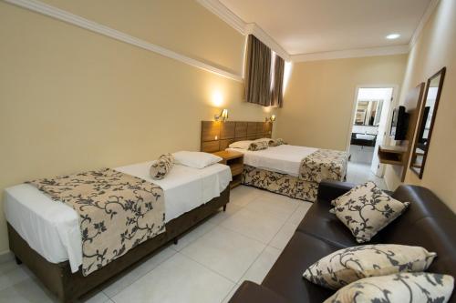 una habitación de hotel con dos camas y un sofá en Wynn Batel, en Curitiba