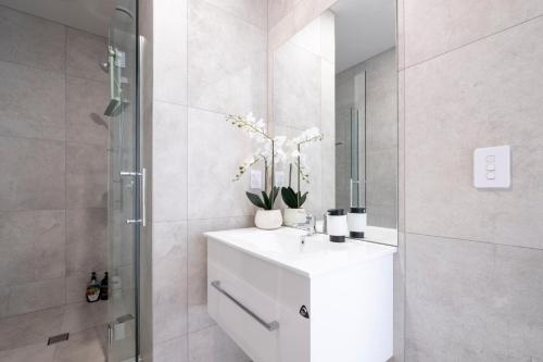 La salle de bains est pourvue d'un lavabo blanc et d'une douche. dans l'établissement Luxury 2 bed townhome in CBD, à Christchurch