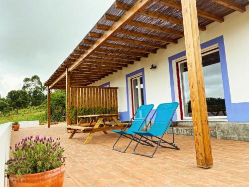 a patio with blue chairs and a wooden table at Monte da Caniveta - Casa dos Compadres in São Luis