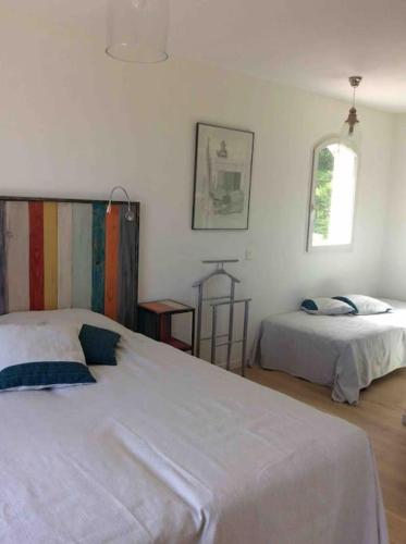 une chambre blanche avec deux lits et une fenêtre dans l'établissement Villa lumineuse et spacieuse, au calme, grande piscine, grand jardin avec oliviers, à Châteauneuf