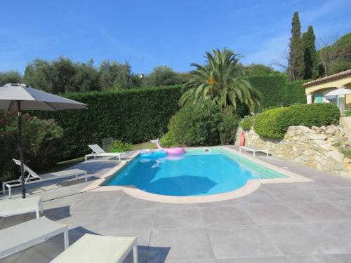 une piscine avec deux chaises et un parasol dans l'établissement Villa lumineuse et spacieuse, au calme, grande piscine, grand jardin avec oliviers, à Châteauneuf