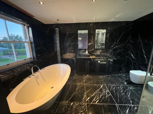 een zwarte badkamer met een bad en een wastafel bij Chigwell Mansion in Theydon Bois