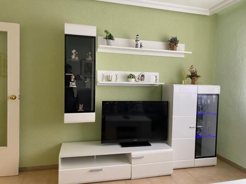 una sala de estar con TV y un centro de entretenimiento blanco en Apartamento junto a la playa, en Peñíscola