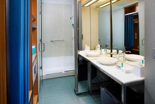 a bathroom with three sinks and a shower at Aloft Philadelphia Airport in Philadelphia