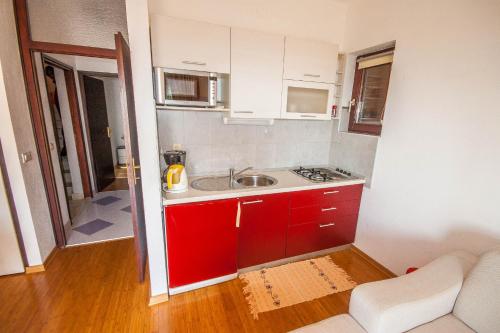 艾克許坦尼的住宿－Apartments Rosanda，一个带水槽和红色橱柜的小厨房