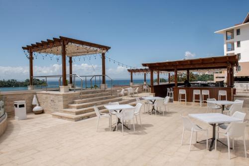 a patio with tables and chairs and the ocean at Hacienda Samana Bay Hotel in Santa Bárbara de Samaná